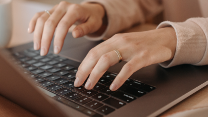 woman with ring typing on her laptop