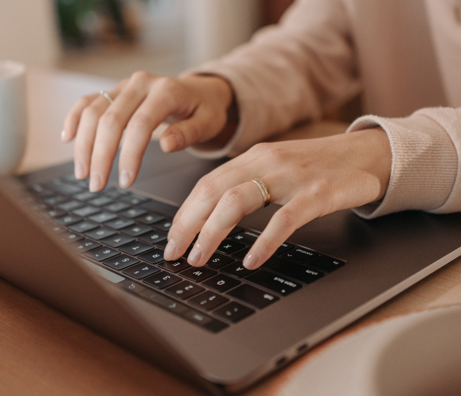 woman with ring typing on her laptop