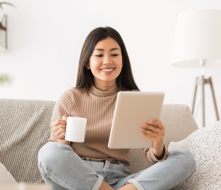 woman holding a cup of coffee while reading business e-books